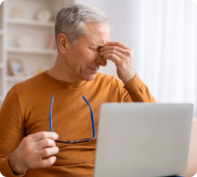 Older adult removing glasses and rubbing their eyes, representing age and lifestyle factors that contribute to dry eye